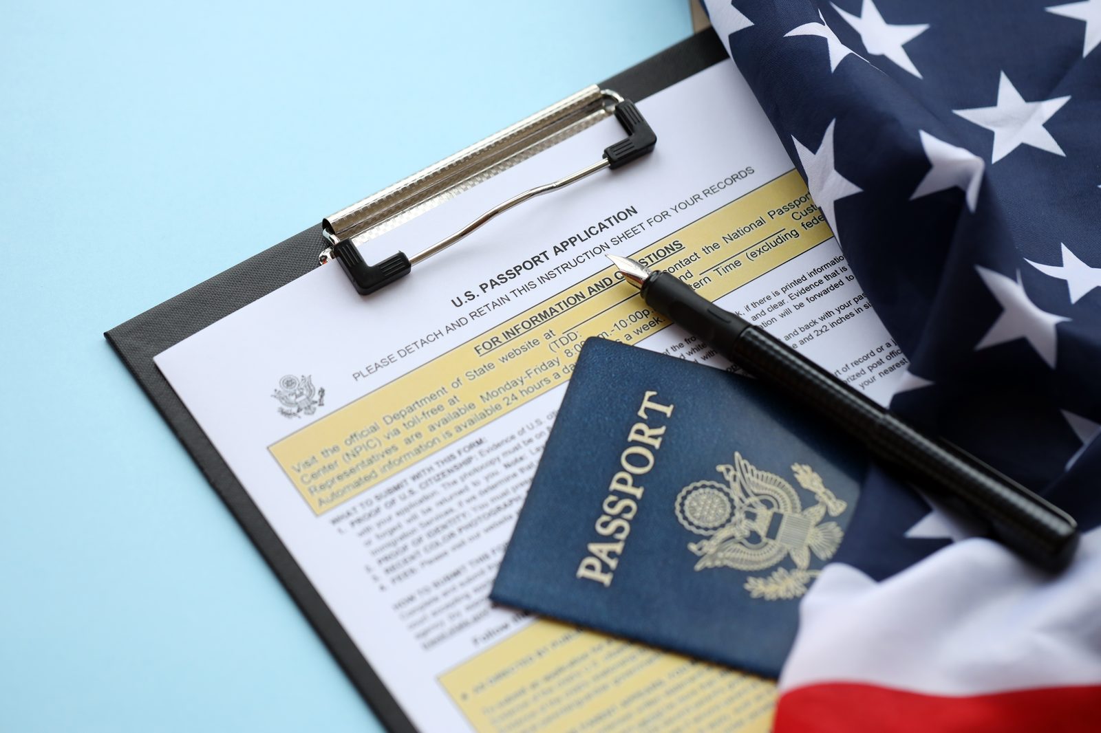 A U.S. passport application clipboard with a passport and folded American flag
