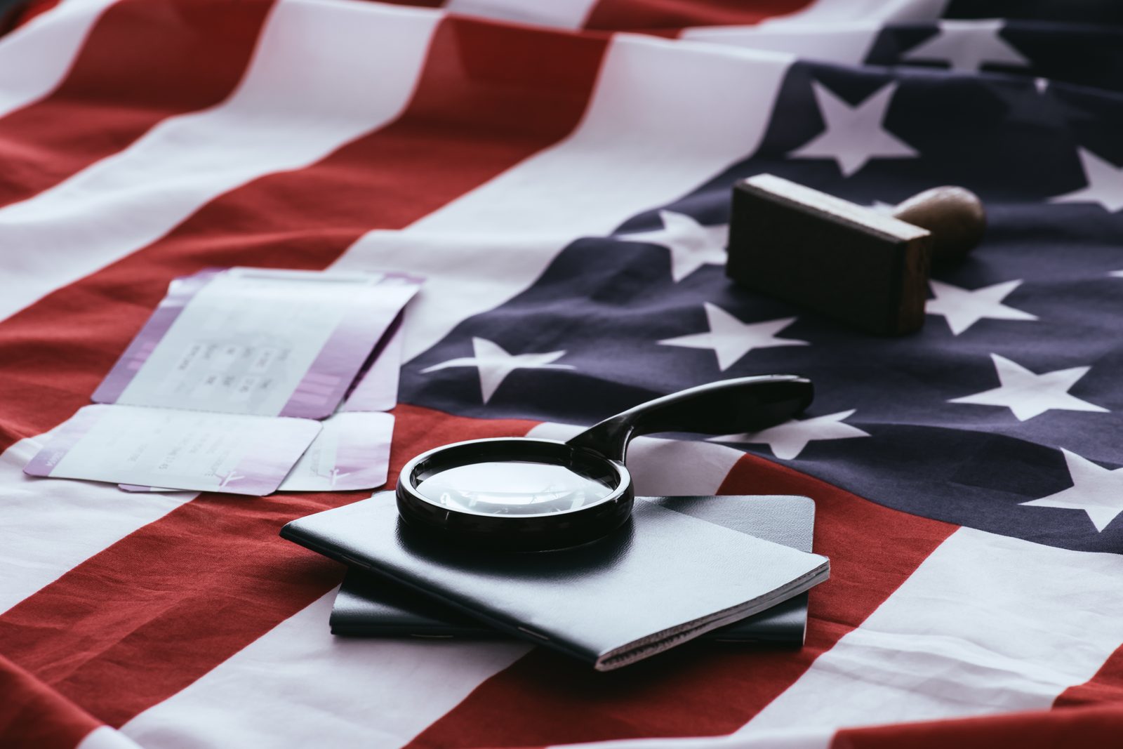 An American flag with a passport and magnifying glass overlaid