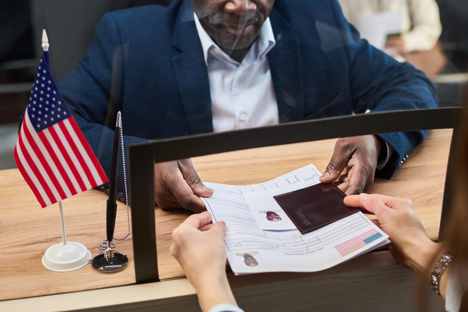 A client handing his passport and documents across a desk to receive help with his immigration paperwork