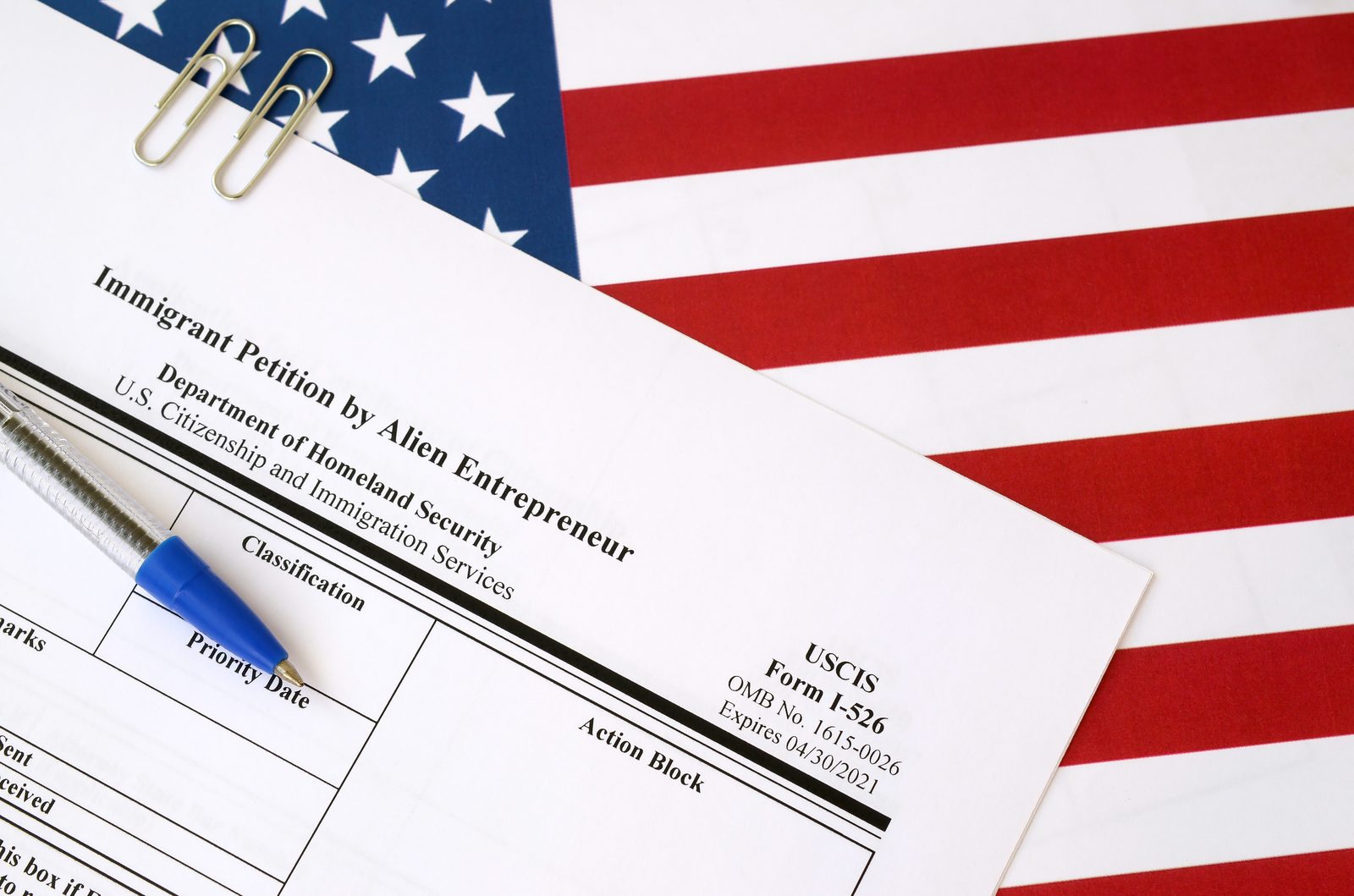 An immigrant petition form on the American flag with a pen, representing employment-based filings