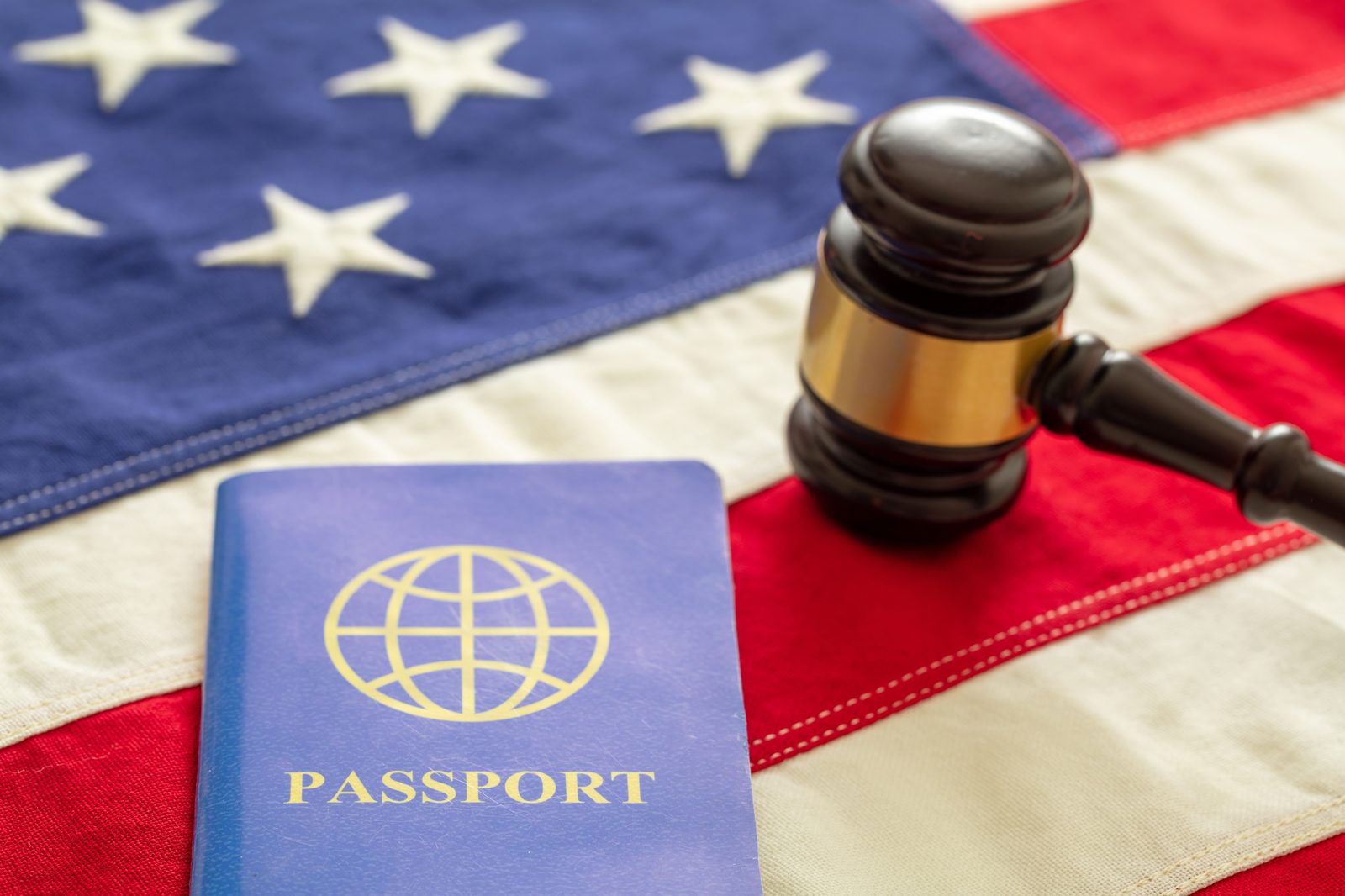 A passport on the American flag, beside a wooden gavel