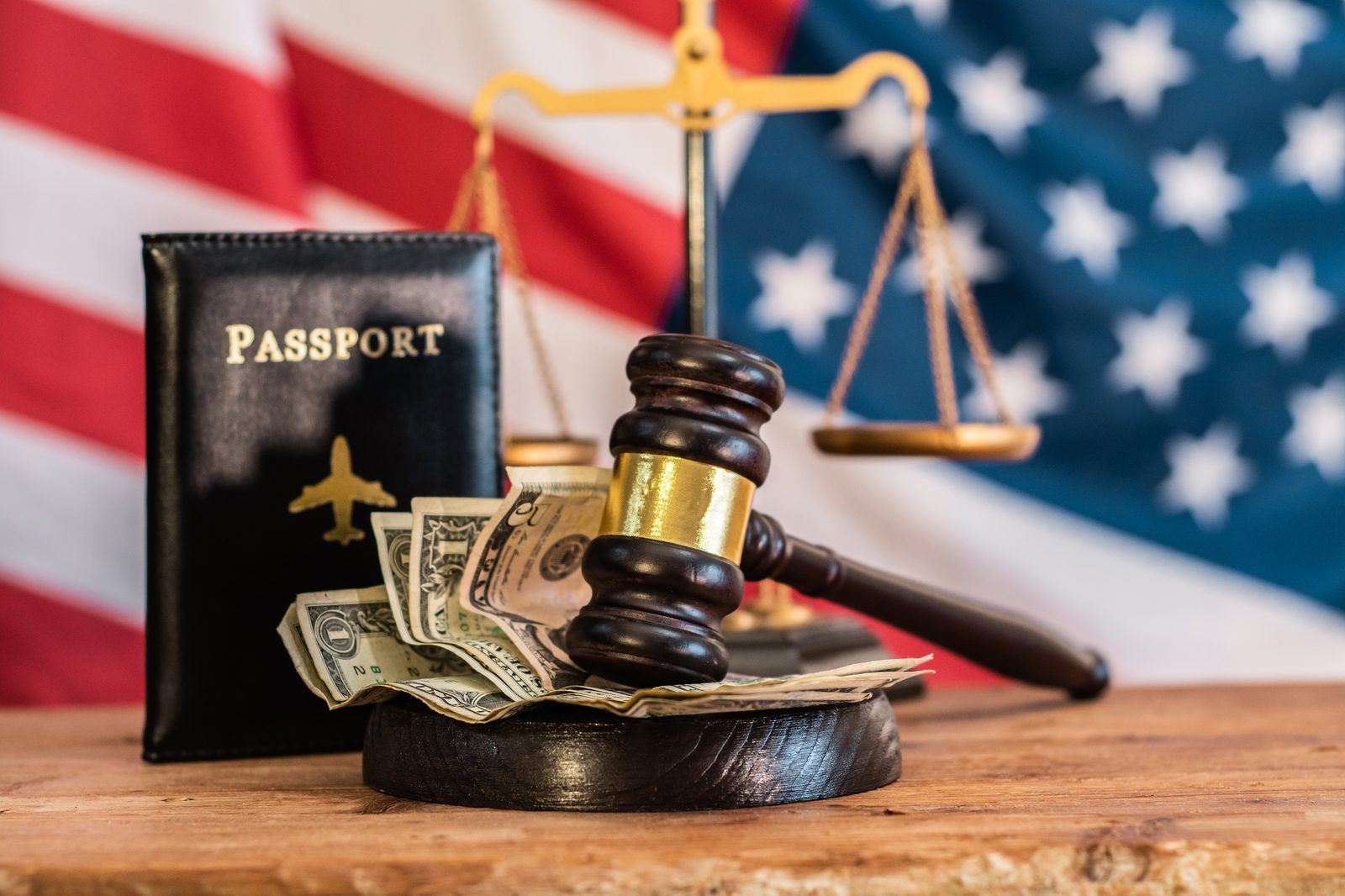 A passport, scales of justice, and the American flag arranged on a wooden surface