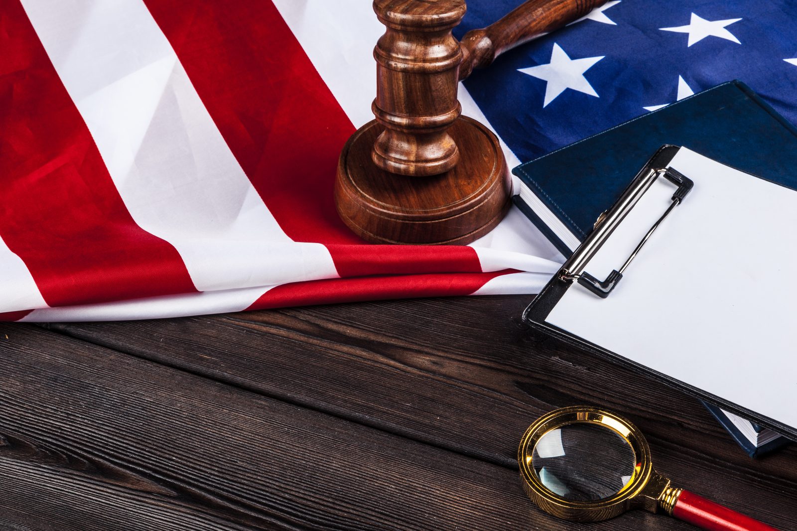 A wooden gavel and a magnifying glass on the American flag