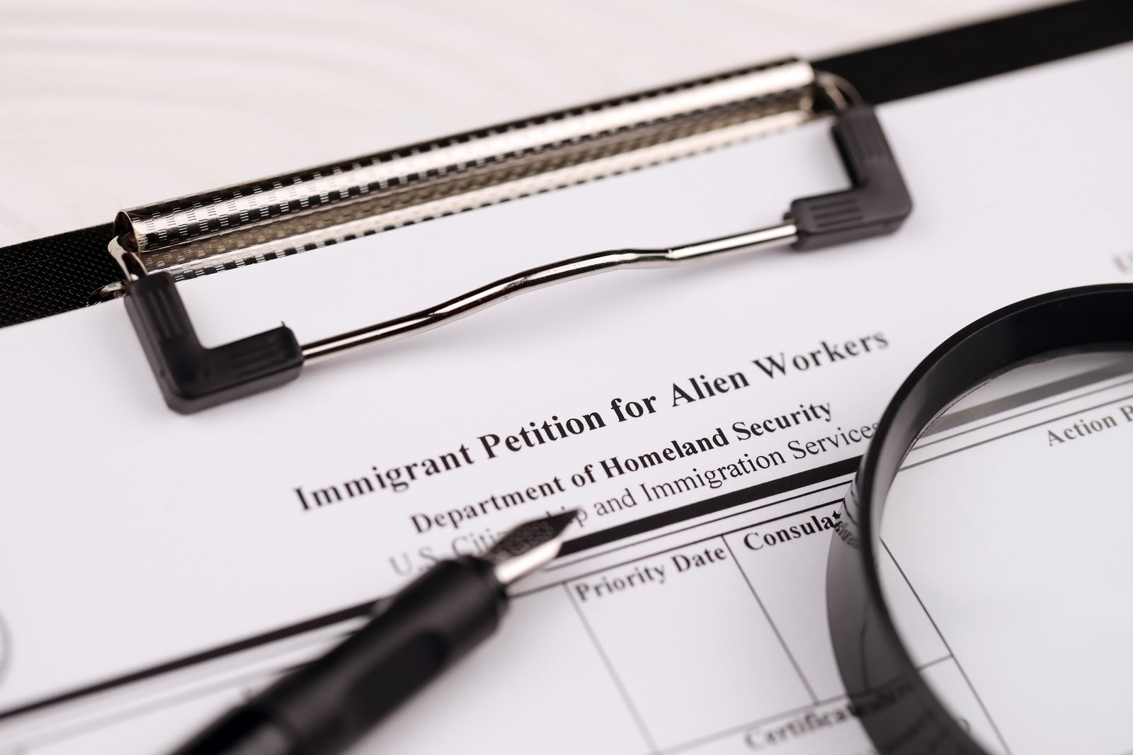 A blank Immigrant Petition for Alien Workers, USCIS Form I-140, with a magnifying glass and pen
